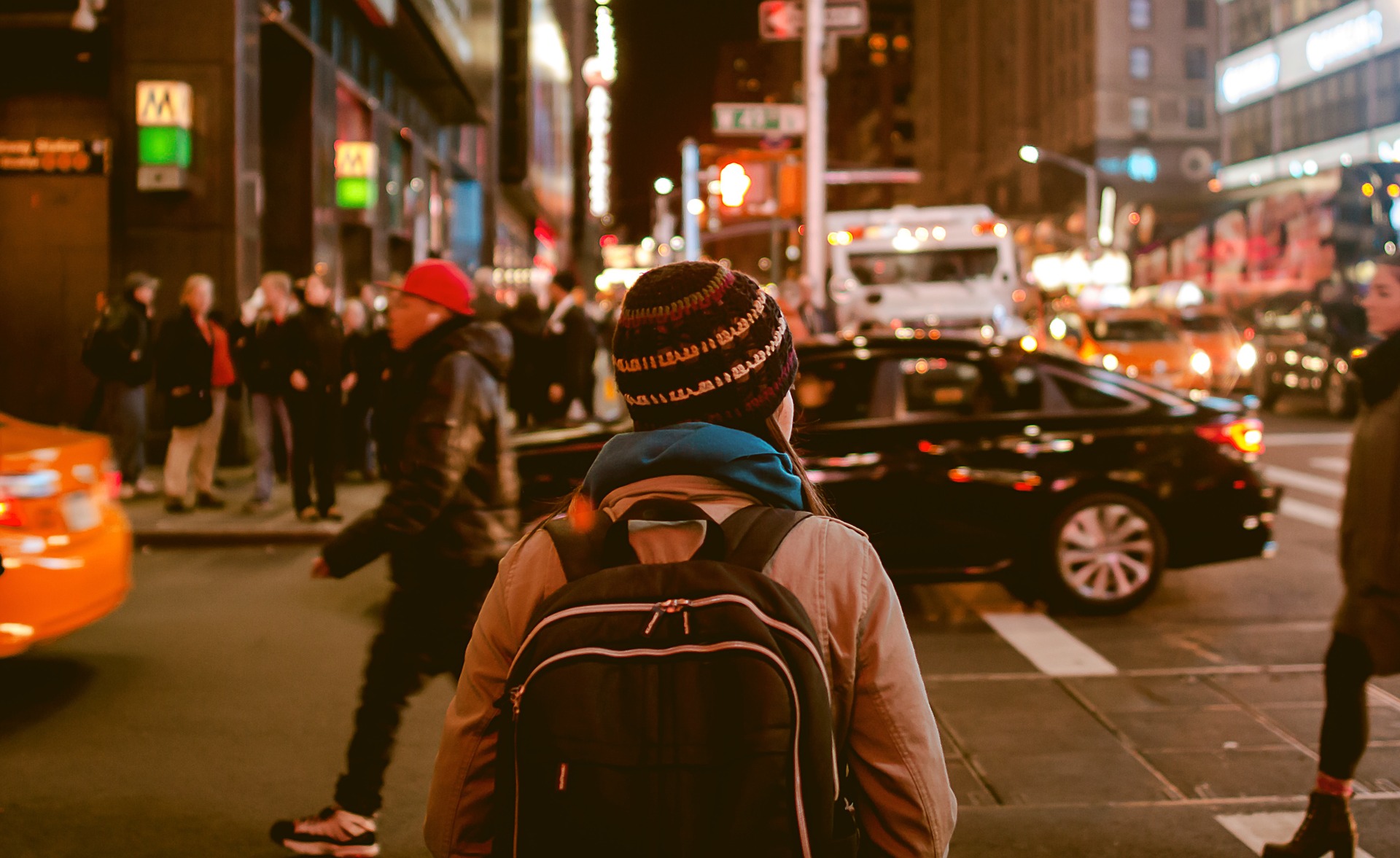 A person standing on the street, facing the traffic.