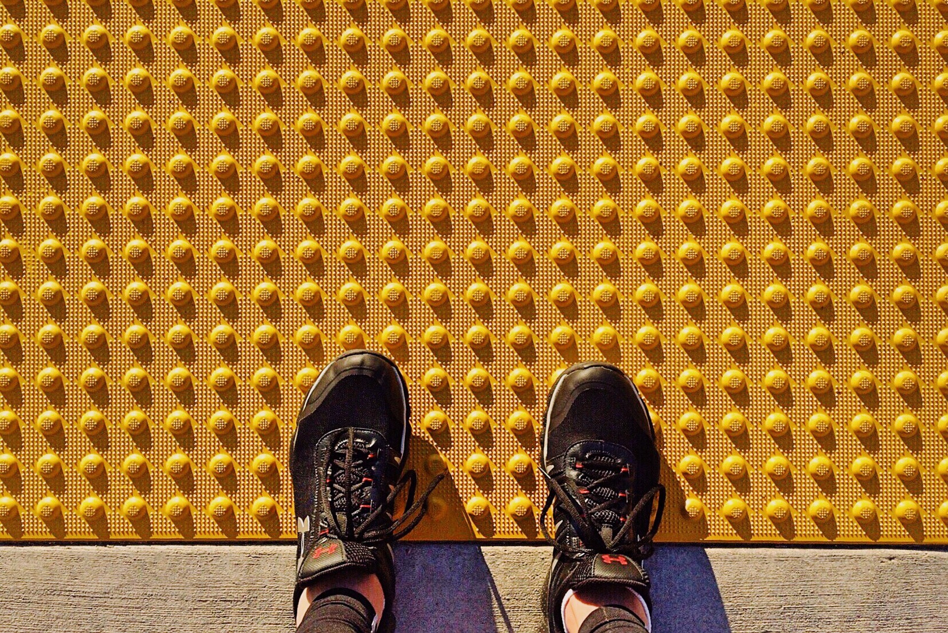Foots on the yellow tactile pavement for visually impaired pedestrians.